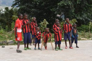 En grupp av barn i röd och svart randiga står tillsammans. En av dem har kryckor