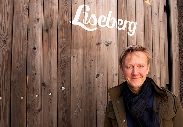 Lisebergs VD Andreas Andersen. En blond man i grön jacka och svart halsduk som står framför ett träplank.