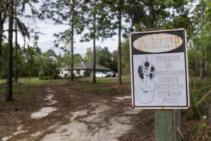 A sign featuring a pistol barrel pointed at would-be trespassers warns, "There is Nothing Here Worth Dying For" at the former home of Charles Newcomb, in Hawthorne, Fla., Thursday, April 15, 2021. Newcomb, the local KKK chapter's leader, known as the Exalted Cyclops, was involved in a 2015 murder plot against a former inmate at a prison where Newcomb once worked as a guard. (AP Photo/David Goldman) FLDG214